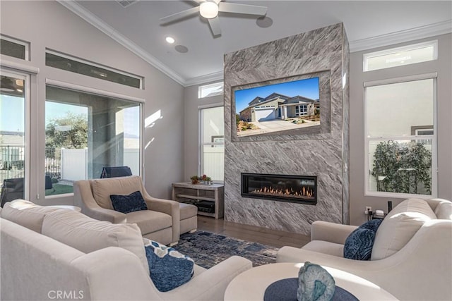 living room featuring hardwood / wood-style flooring, a tile fireplace, ornamental molding, and vaulted ceiling