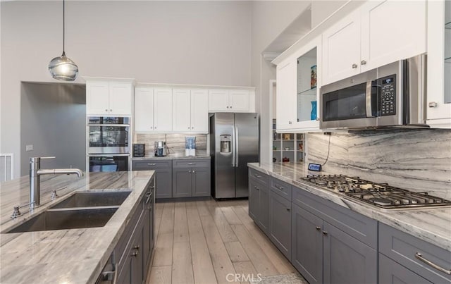 kitchen featuring light stone countertops, white cabinets, appliances with stainless steel finishes, and sink