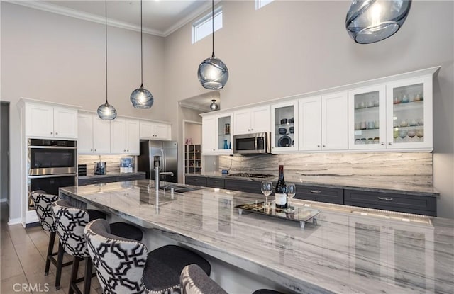 kitchen with white cabinetry, stainless steel appliances, tasteful backsplash, hanging light fixtures, and sink