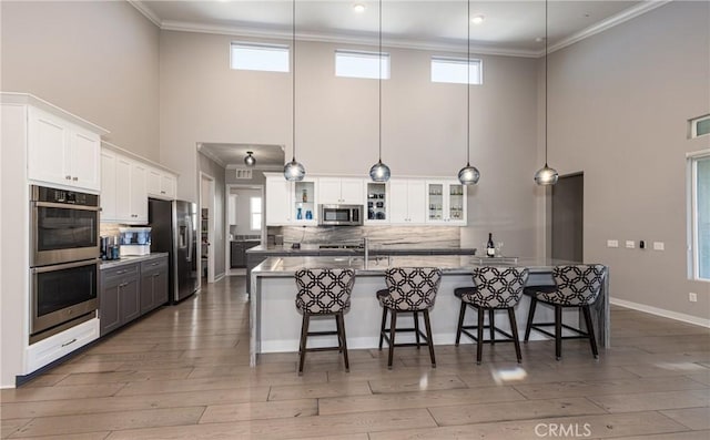 kitchen with white cabinets, appliances with stainless steel finishes, and pendant lighting