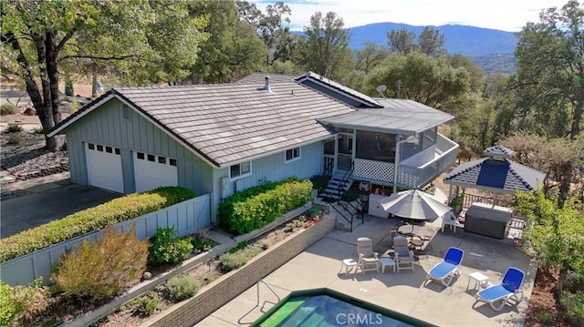 back of property featuring a sunroom, a mountain view, a gazebo, a patio area, and a garage