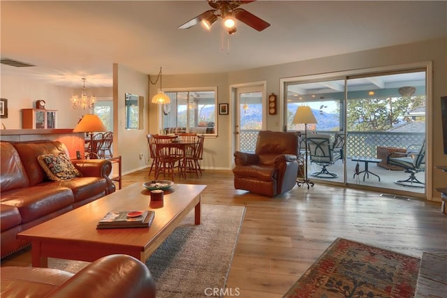 living room with hardwood / wood-style floors, a healthy amount of sunlight, and ceiling fan with notable chandelier