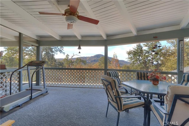 sunroom with a mountain view, beamed ceiling, and ceiling fan