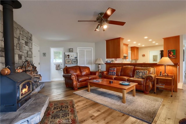 living room featuring ceiling fan, light wood-type flooring, and a wood stove