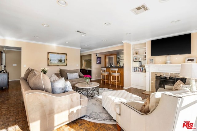 living room featuring indoor bar, built in features, dark parquet floors, and ornamental molding