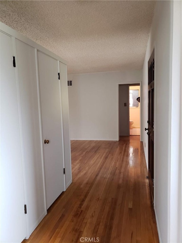 hallway with a textured ceiling and hardwood / wood-style flooring