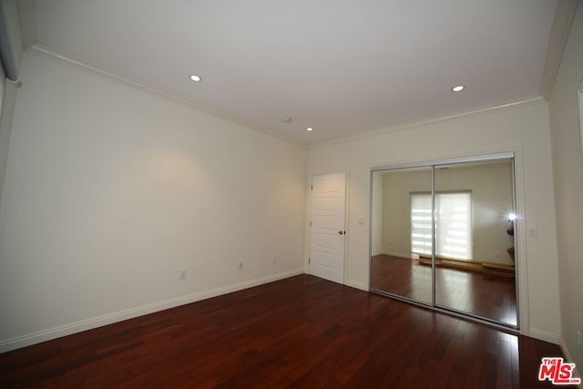 unfurnished bedroom featuring dark hardwood / wood-style floors, ornamental molding, and a closet