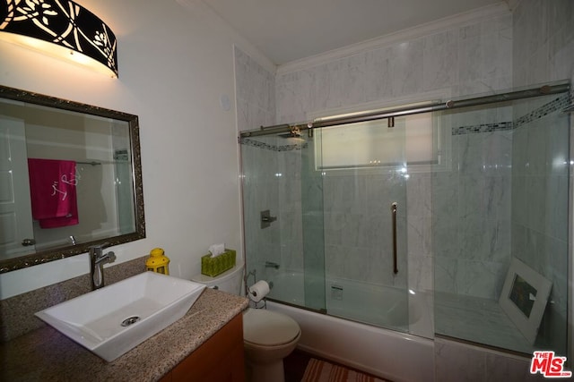 full bathroom featuring vanity, toilet, shower / bath combination with glass door, and ornamental molding