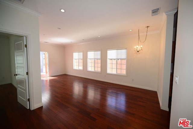 empty room featuring dark hardwood / wood-style floors, crown molding, and an inviting chandelier