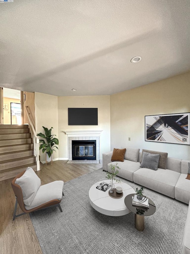 living room with wood-type flooring, a fireplace, and a textured ceiling