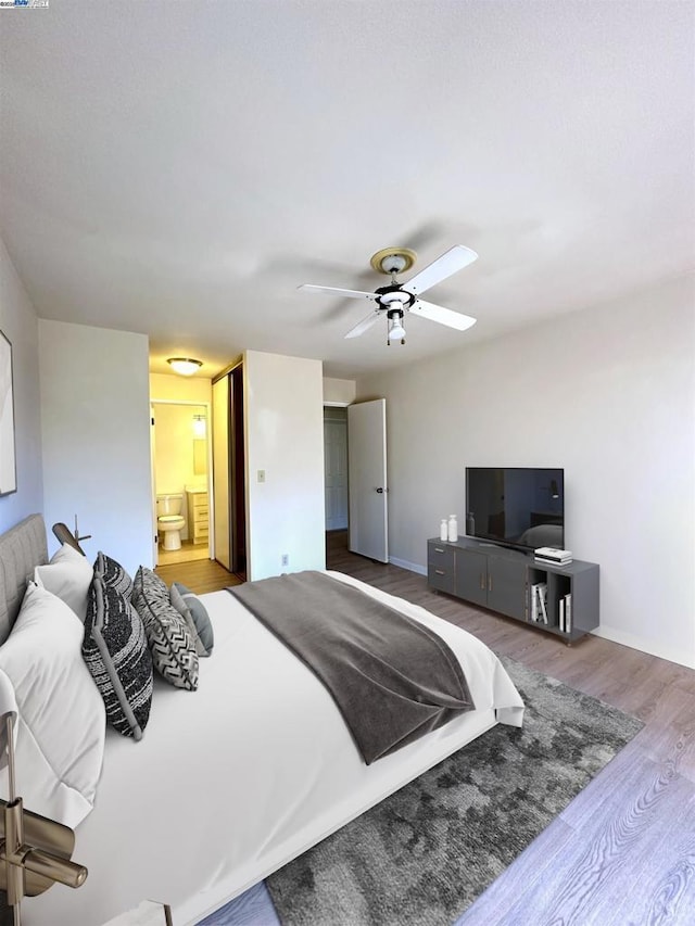 bedroom with ensuite bath, ceiling fan, and hardwood / wood-style flooring