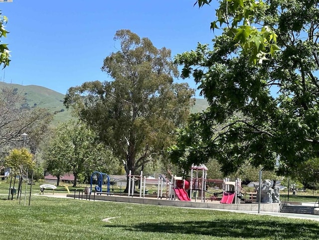 view of playground featuring a mountain view and a lawn