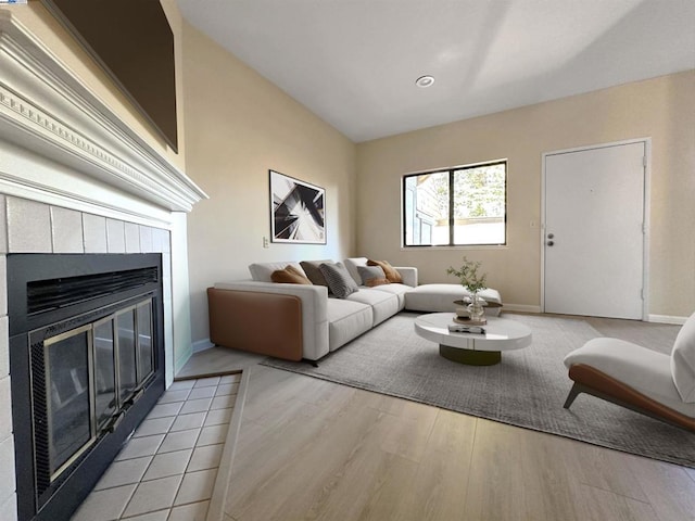 living room with a tiled fireplace and light hardwood / wood-style floors