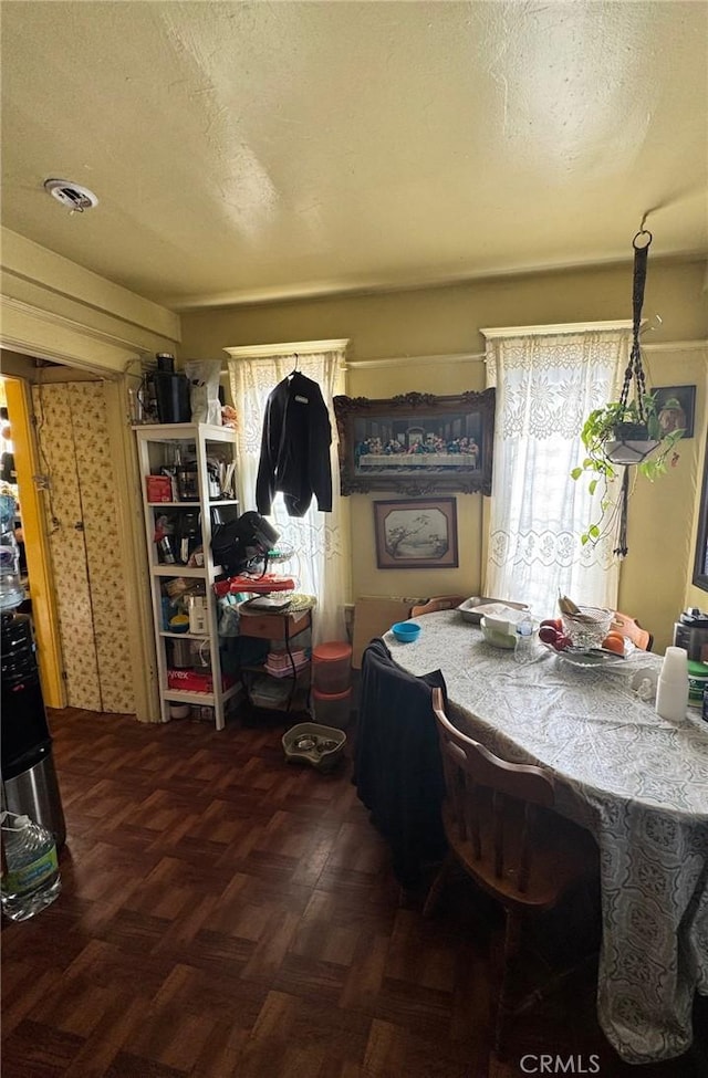 dining area featuring plenty of natural light, a textured ceiling, and dark parquet floors