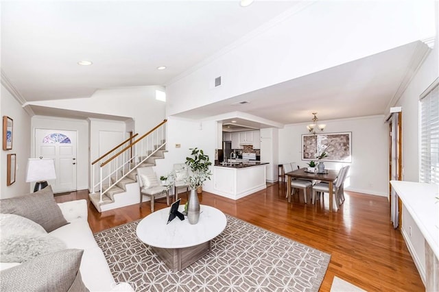 living room featuring lofted ceiling, a notable chandelier, crown molding, and hardwood / wood-style floors