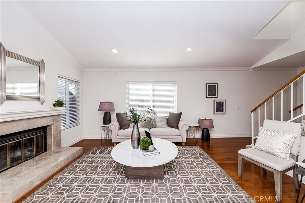 living room featuring dark hardwood / wood-style flooring, a high end fireplace, crown molding, and vaulted ceiling