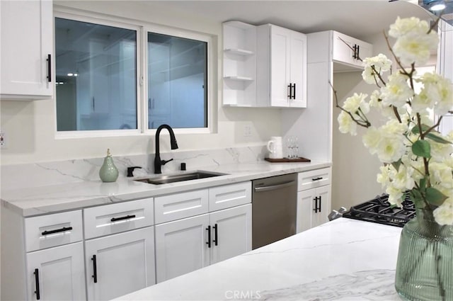 kitchen featuring stainless steel dishwasher, white cabinets, light stone counters, and sink