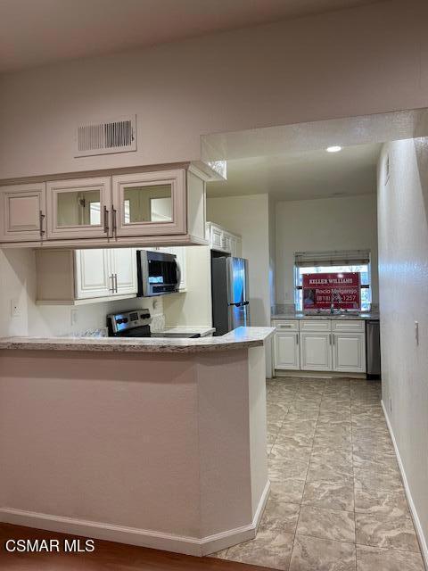 kitchen with white cabinets, stainless steel appliances, kitchen peninsula, and sink