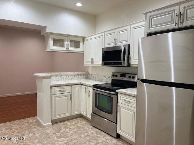 kitchen with light stone countertops, appliances with stainless steel finishes, light tile patterned floors, and white cabinetry