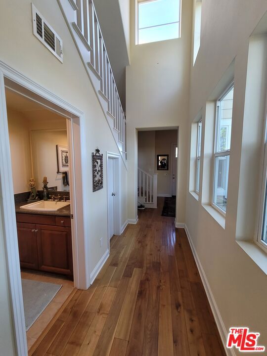 corridor with a towering ceiling, dark hardwood / wood-style flooring, and sink