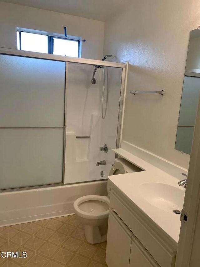 full bathroom with vanity, bath / shower combo with glass door, and toilet