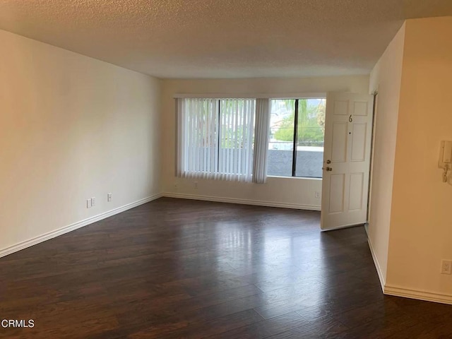 unfurnished room featuring dark wood-type flooring and a textured ceiling