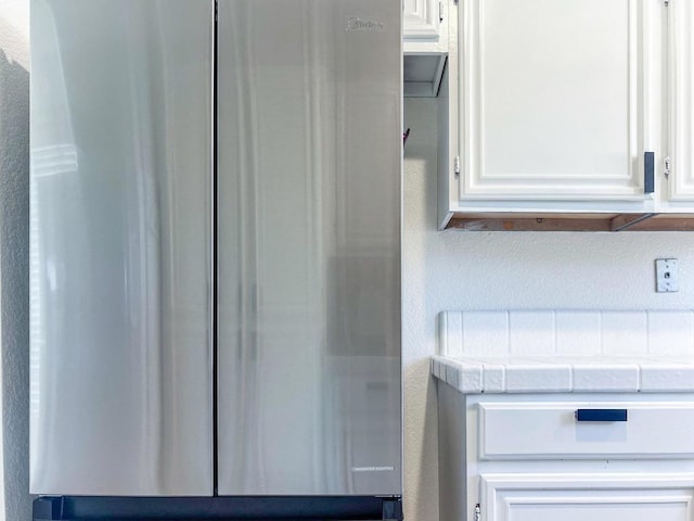 details featuring tile countertops and white cabinets