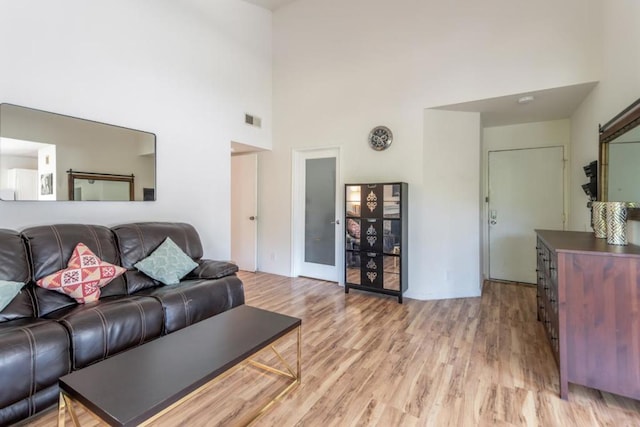 living room with a towering ceiling and light hardwood / wood-style flooring