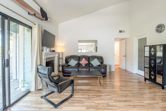 living room featuring high vaulted ceiling and light hardwood / wood-style flooring