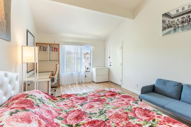 bedroom with lofted ceiling with beams, wood-type flooring, and refrigerator