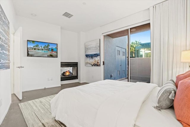 bedroom featuring concrete floors, a multi sided fireplace, and access to outside