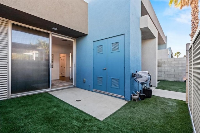 view of exterior entry with a yard and a patio