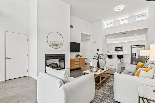 living room featuring a towering ceiling and a multi sided fireplace