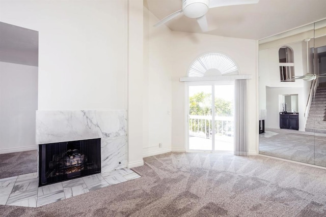 unfurnished living room with ceiling fan, light carpet, and a premium fireplace