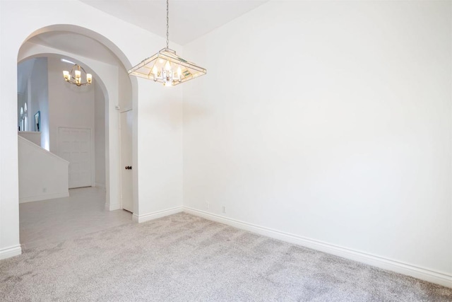 carpeted spare room featuring a chandelier