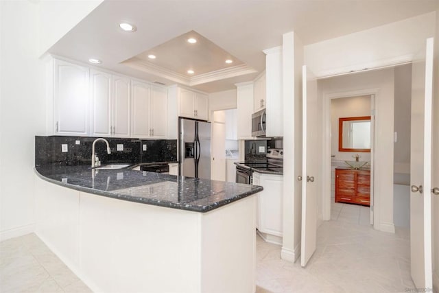 kitchen featuring appliances with stainless steel finishes, white cabinetry, sink, a raised ceiling, and kitchen peninsula