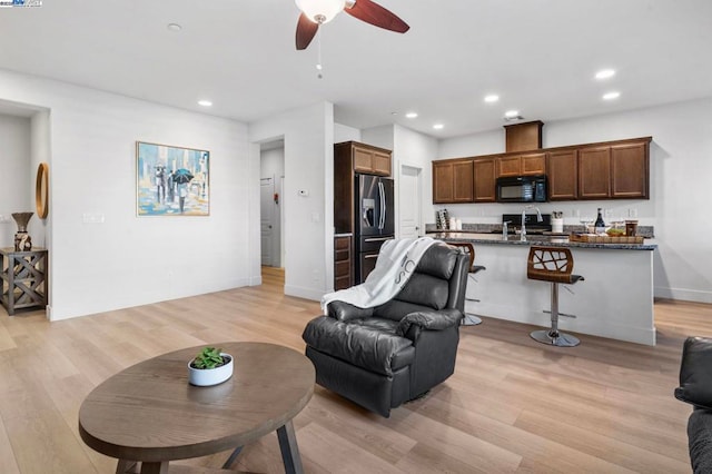 living room with light hardwood / wood-style floors, ceiling fan, and sink