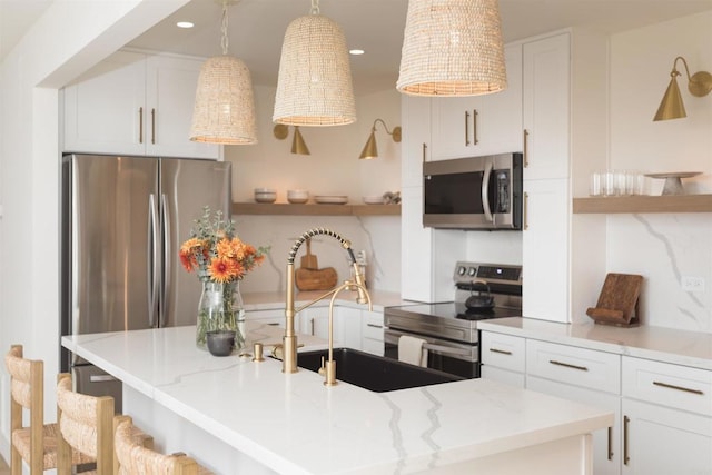 kitchen featuring light stone countertops, stainless steel appliances, white cabinetry, and hanging light fixtures