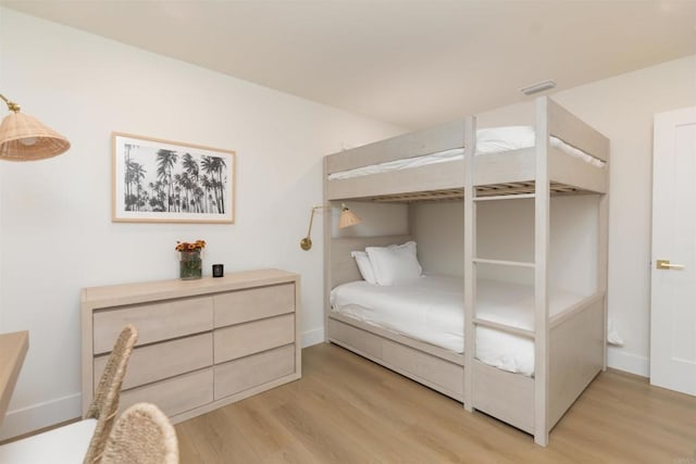 bedroom with baseboards, visible vents, and light wood finished floors