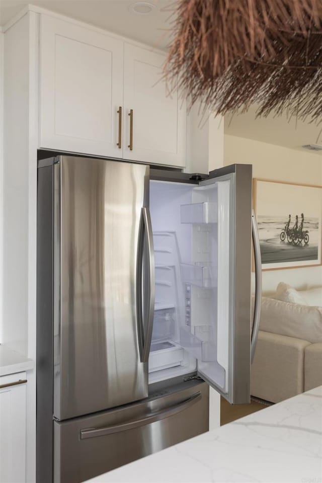 room details featuring light stone countertops, white cabinets, and freestanding refrigerator