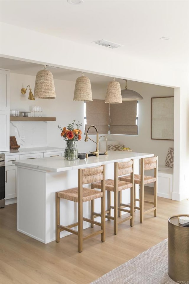 kitchen with light countertops, decorative light fixtures, a kitchen breakfast bar, and white cabinetry