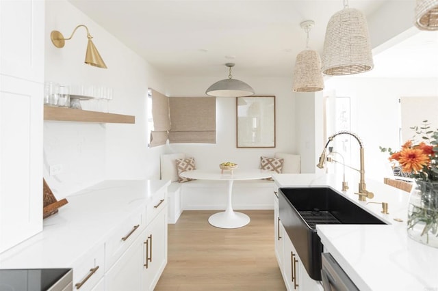 kitchen with breakfast area, a sink, decorative light fixtures, and white cabinets