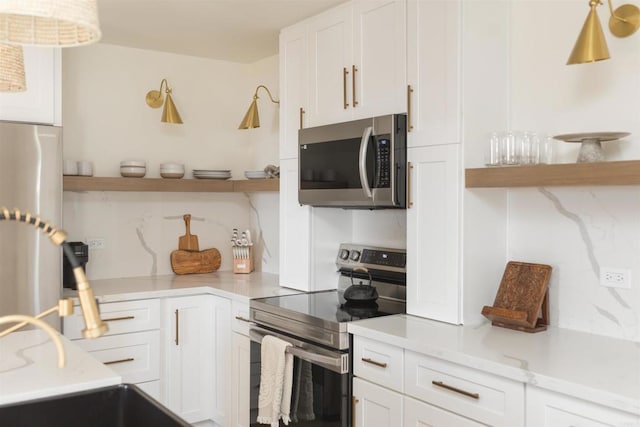 kitchen with stainless steel appliances, white cabinets, light stone countertops, open shelves, and tasteful backsplash