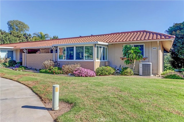 single story home featuring a front lawn and central air condition unit