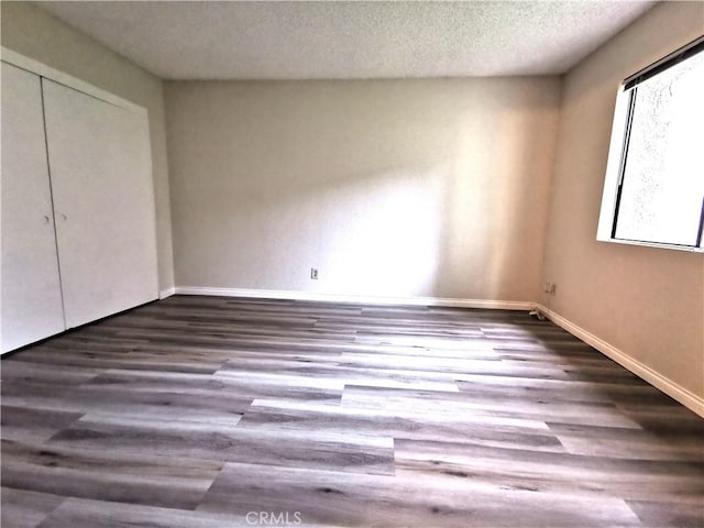 unfurnished bedroom with dark hardwood / wood-style floors, a textured ceiling, and a closet