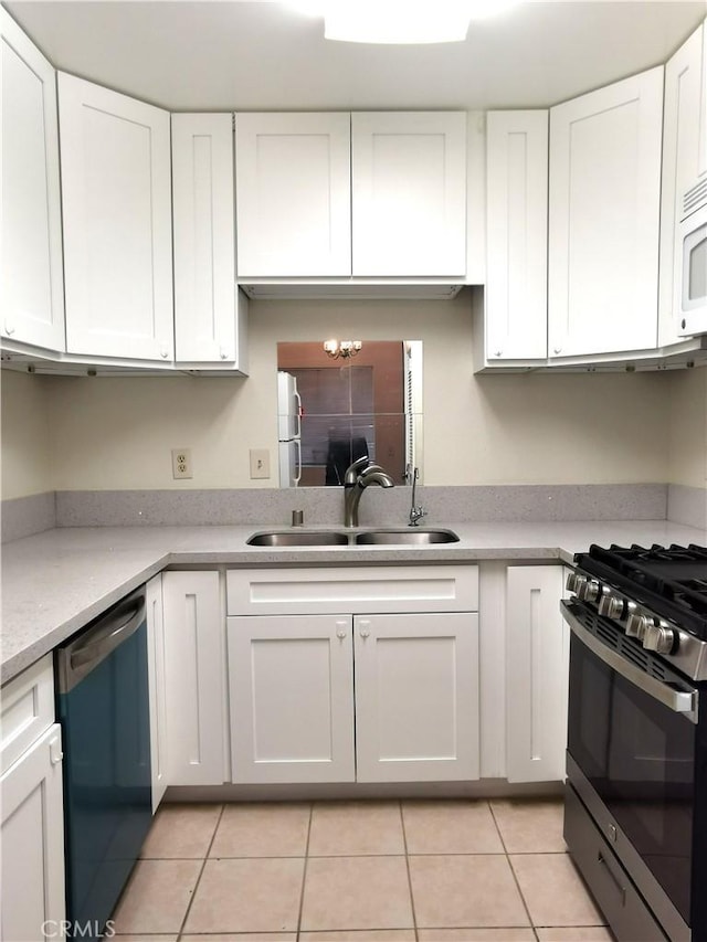 kitchen with an inviting chandelier, sink, light tile patterned floors, appliances with stainless steel finishes, and white cabinetry