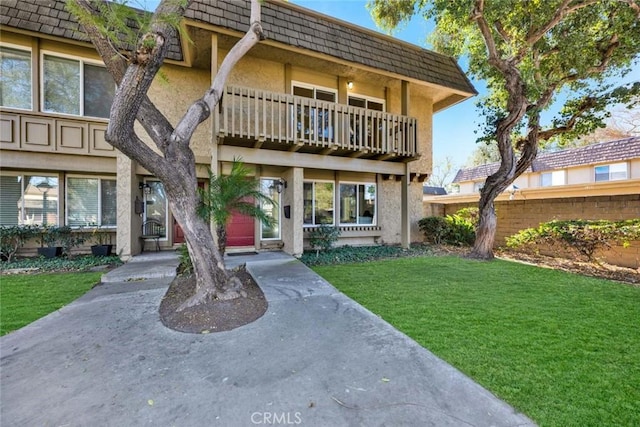 view of front of house with a balcony and a front yard