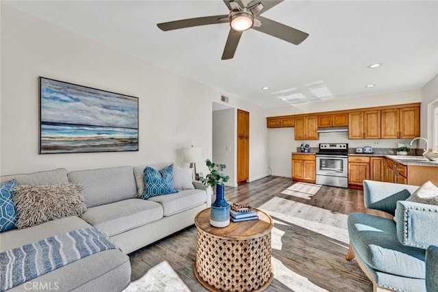 living room with dark hardwood / wood-style flooring, ceiling fan, and sink