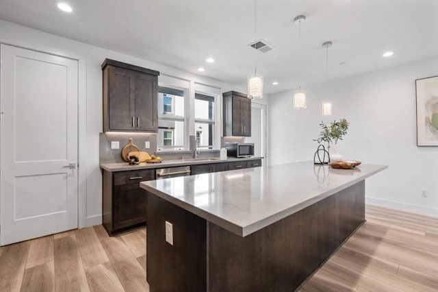 kitchen with stainless steel appliances, a kitchen island, dark brown cabinetry, and decorative light fixtures