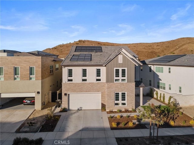 view of front of house featuring a garage, a mountain view, and solar panels